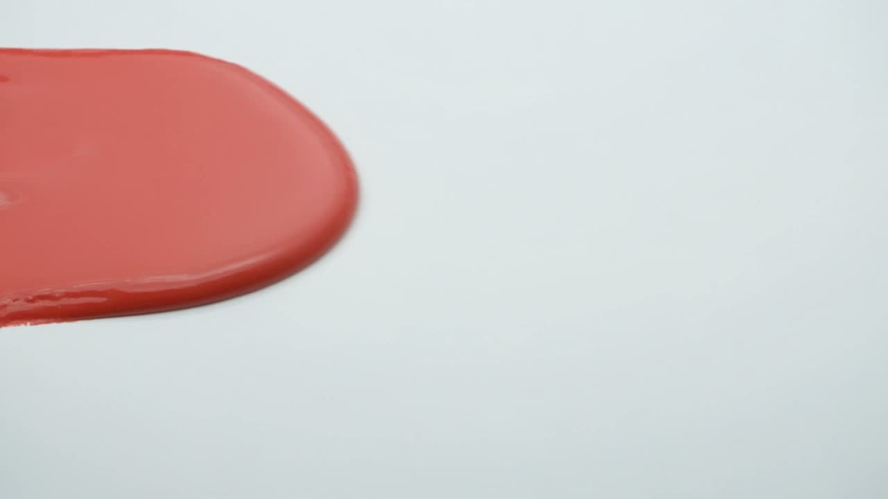 Still frame: a slab of vermilion paint folding across a bone-white floor